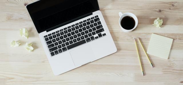 turned off MacBook Pro beside white ceramic mug filled with coffee photo